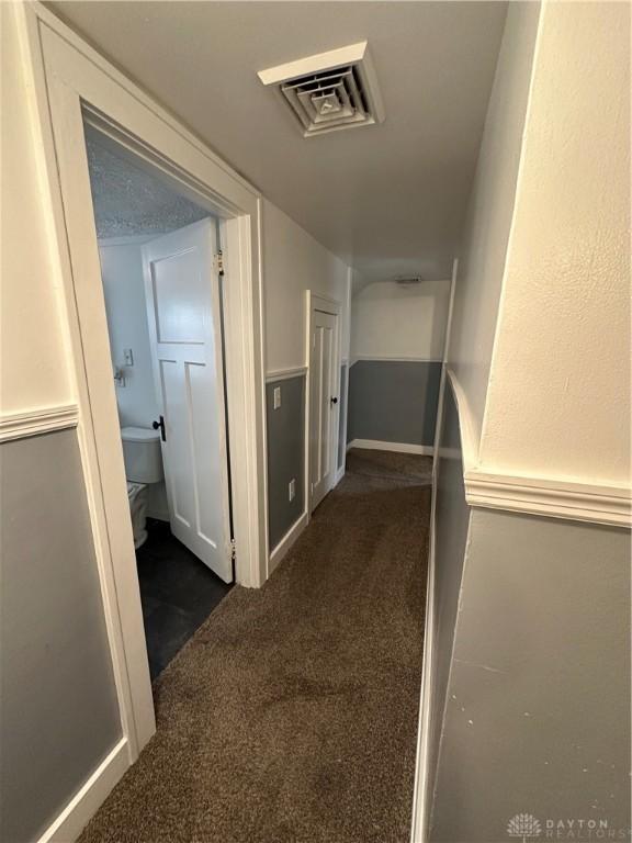 hallway featuring dark colored carpet