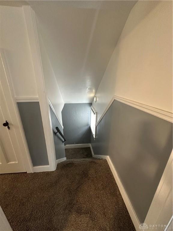 stairs with lofted ceiling and carpet floors