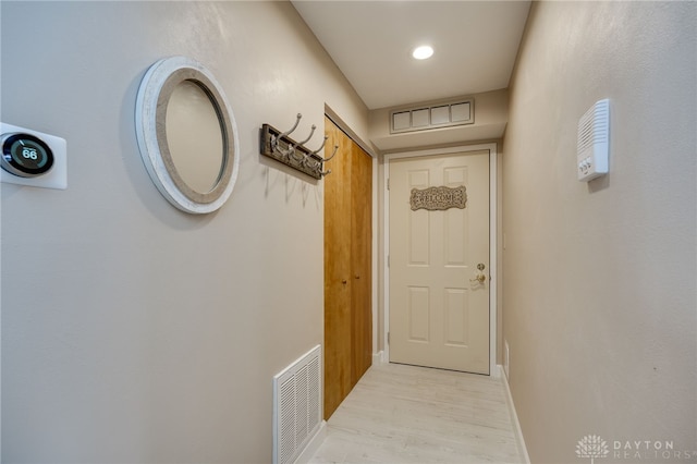 doorway with light wood-style floors, baseboards, and visible vents