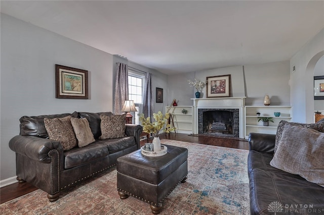 living room featuring hardwood / wood-style flooring, built in shelves, and a high end fireplace