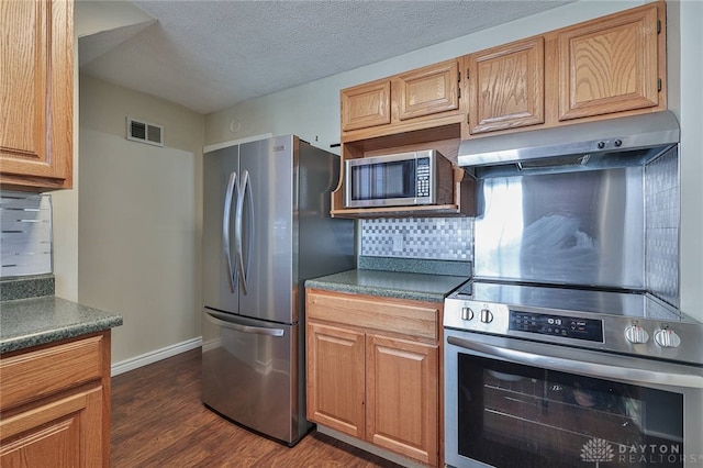 kitchen with a textured ceiling, decorative backsplash, appliances with stainless steel finishes, and dark hardwood / wood-style flooring