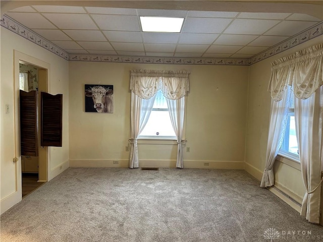 carpeted empty room with a drop ceiling