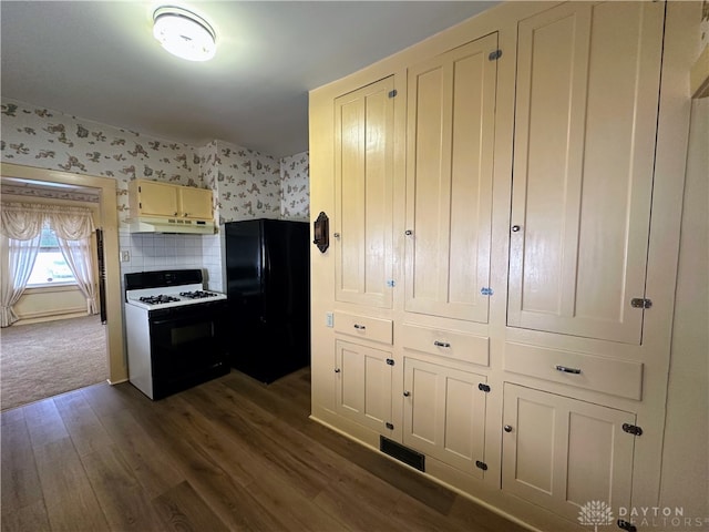 kitchen with black refrigerator, gas stove, and dark hardwood / wood-style floors