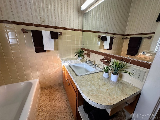 bathroom with tile walls, vanity, and a bathtub