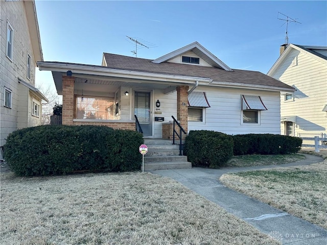 bungalow-style house with a front lawn, covered porch, and brick siding