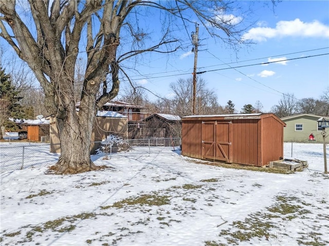 yard covered in snow with an outbuilding, fence, and a shed