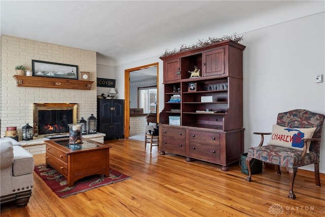 living area featuring a brick fireplace and light wood-style flooring