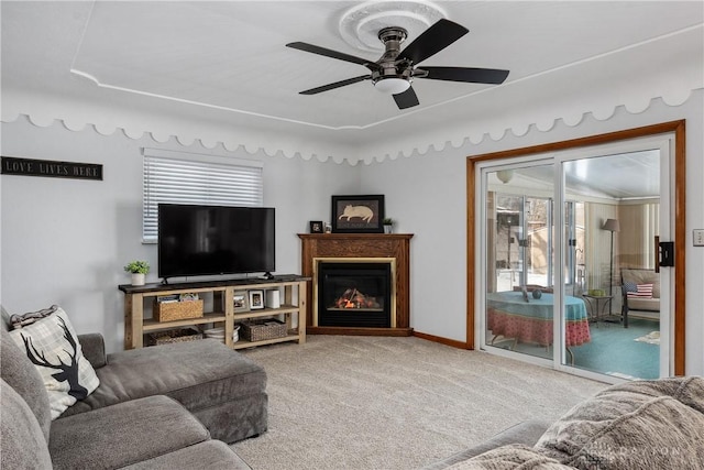 living room with a healthy amount of sunlight, ceiling fan, a glass covered fireplace, and light colored carpet