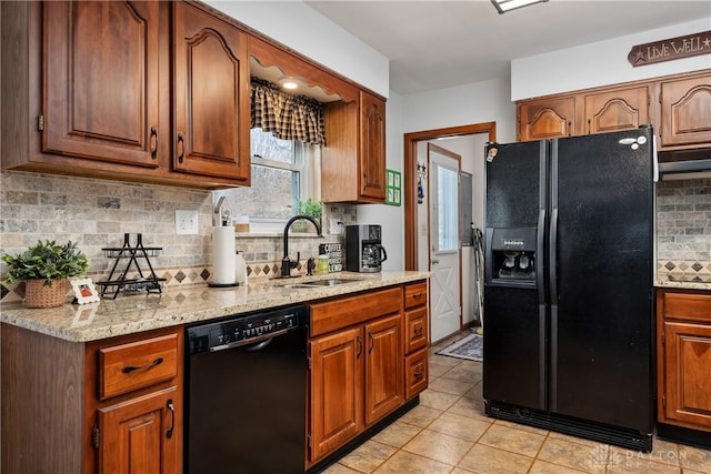 kitchen featuring light stone countertops, black appliances, brown cabinetry, and a sink