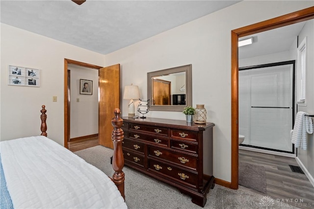 bedroom with light wood-style floors, connected bathroom, visible vents, and baseboards