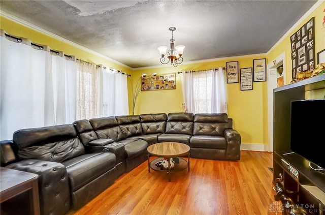 living room featuring a textured ceiling, ornamental molding, wood finished floors, and a notable chandelier