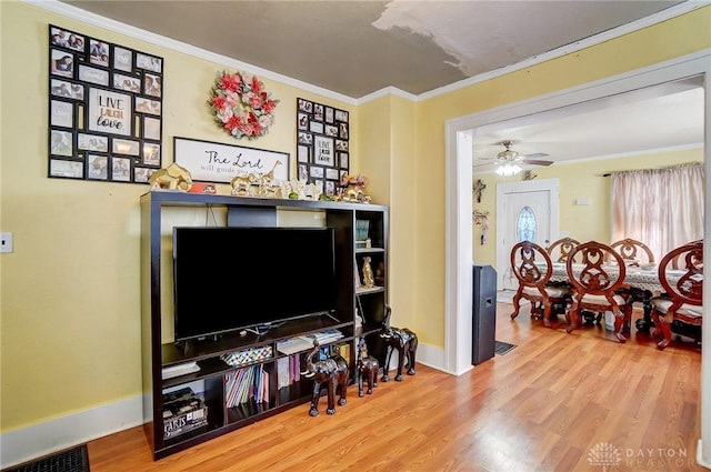 living room featuring ceiling fan, wood finished floors, visible vents, baseboards, and crown molding