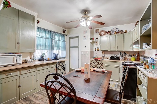 kitchen with stainless steel electric stove, light countertops, white microwave, and open shelves