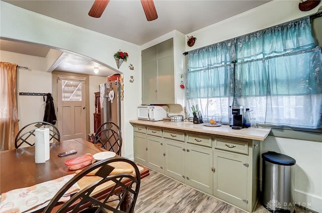 kitchen with light wood finished floors, ceiling fan, arched walkways, and light countertops