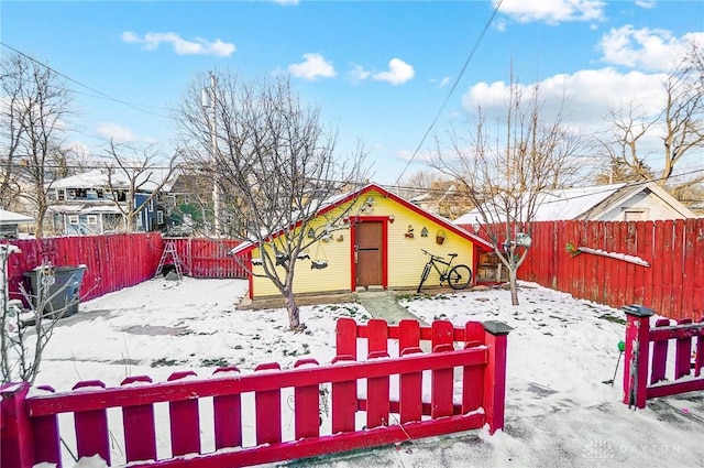 snowy yard featuring a fenced backyard and an outdoor structure