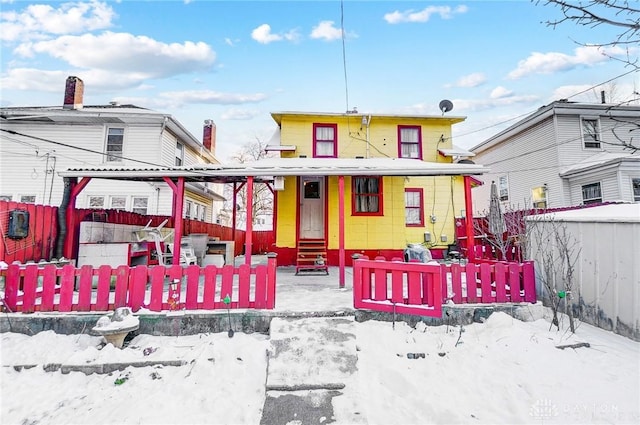 snow covered rear of property with a fenced front yard