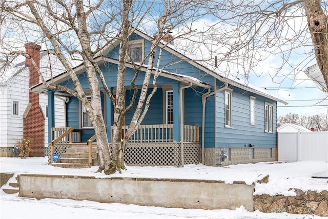 bungalow-style house featuring a porch, fence, and a chimney