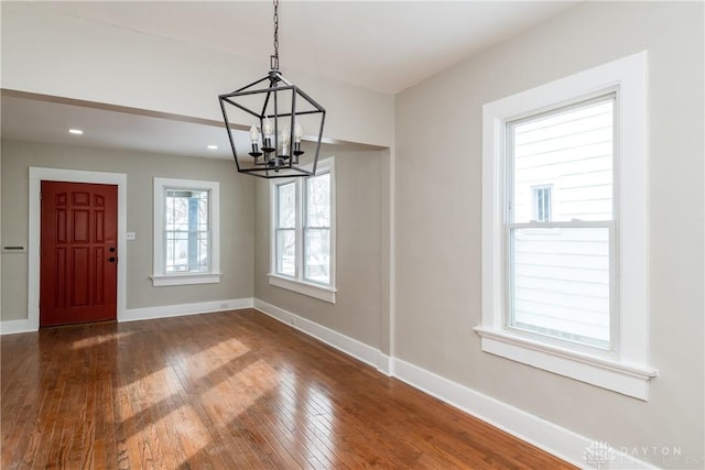 unfurnished dining area featuring recessed lighting, an inviting chandelier, wood finished floors, and baseboards