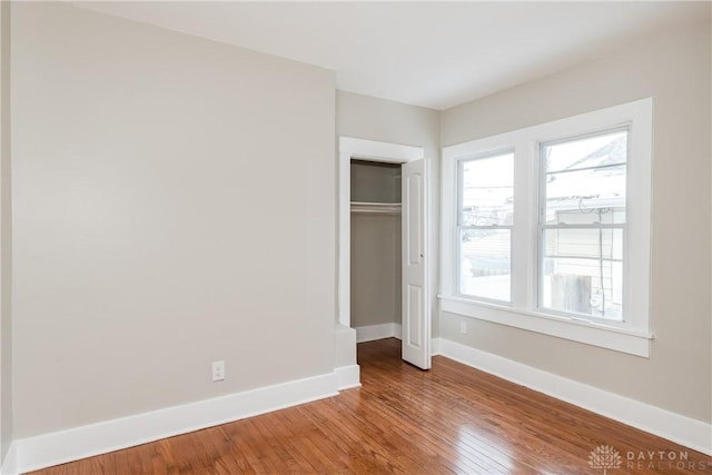 unfurnished bedroom with a closet, baseboards, and wood finished floors