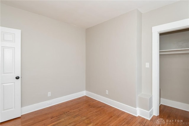 unfurnished bedroom with a closet, baseboards, and wood finished floors