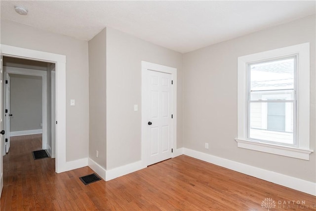 interior space featuring a closet, wood finished floors, visible vents, and baseboards