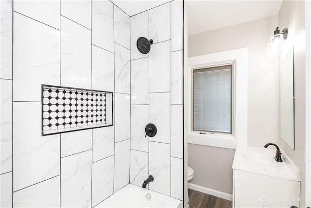 full bathroom with baseboards, toilet, vanity, wood finished floors, and shower / bathtub combination