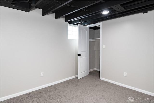 below grade area featuring baseboards and carpet flooring