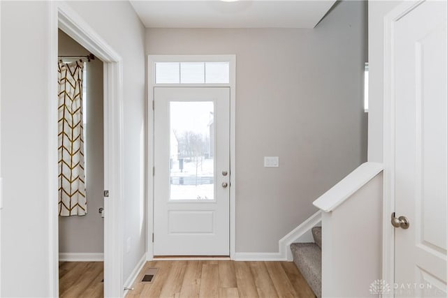 entryway with light wood-style flooring, visible vents, stairway, and baseboards