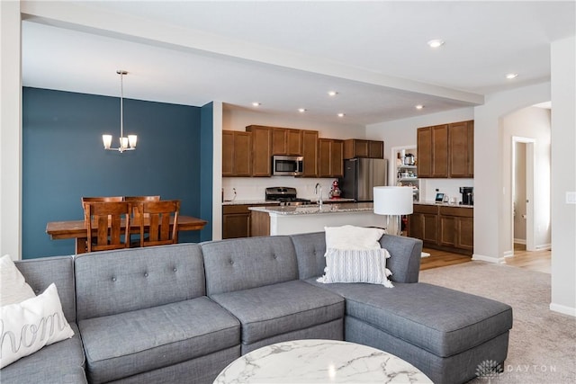 living room featuring arched walkways, recessed lighting, light colored carpet, a notable chandelier, and baseboards