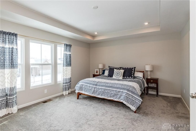 bedroom featuring carpet floors, a tray ceiling, recessed lighting, visible vents, and baseboards