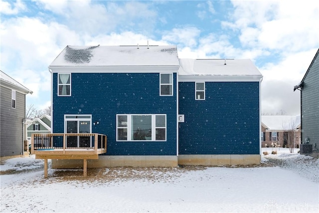 snow covered rear of property featuring a deck, central AC, and brick siding