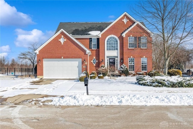 colonial home featuring an attached garage, fence, brick siding, and driveway