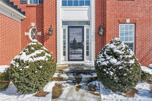 snow covered property entrance with brick siding