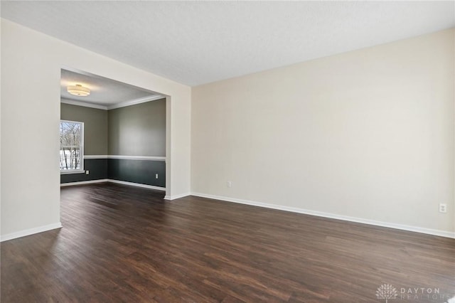 spare room with baseboards and dark wood-style flooring