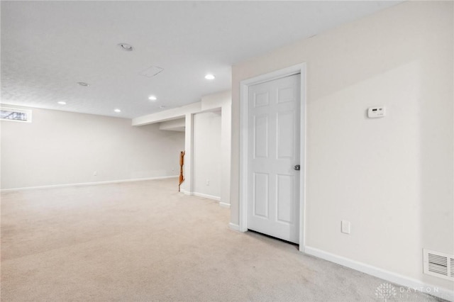 finished below grade area featuring light carpet, visible vents, recessed lighting, and baseboards