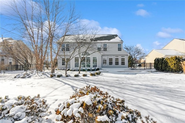 snow covered back of property featuring fence