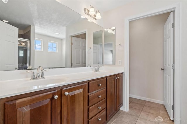 full bathroom featuring tile patterned floors, double vanity, a textured ceiling, and a sink