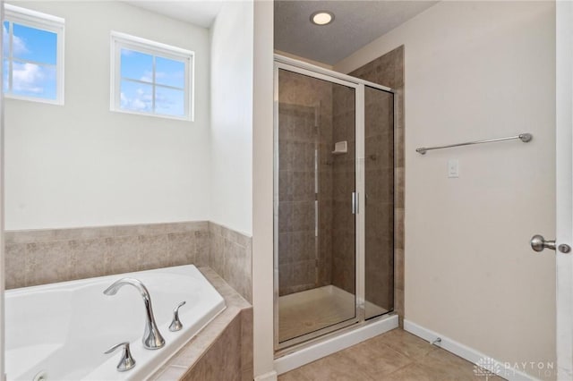 bathroom featuring baseboards, a garden tub, a shower stall, and tile patterned flooring