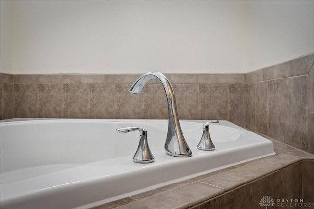 room details with a relaxing tiled tub and a sink