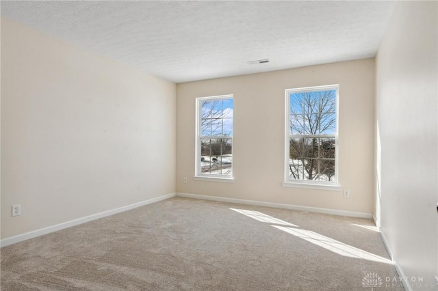 empty room featuring visible vents, baseboards, carpet floors, and a textured ceiling