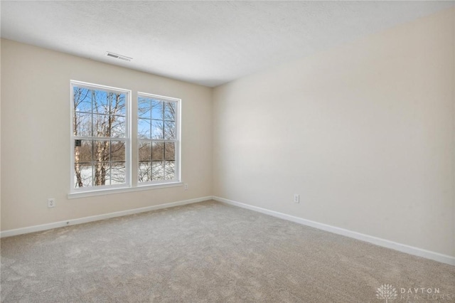 carpeted empty room with visible vents, a textured ceiling, and baseboards