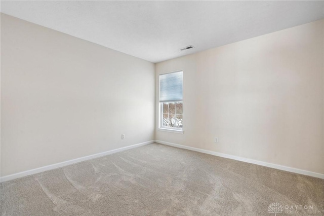 empty room with carpet flooring, baseboards, and visible vents