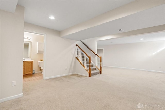 finished basement with baseboards, visible vents, recessed lighting, stairs, and light carpet