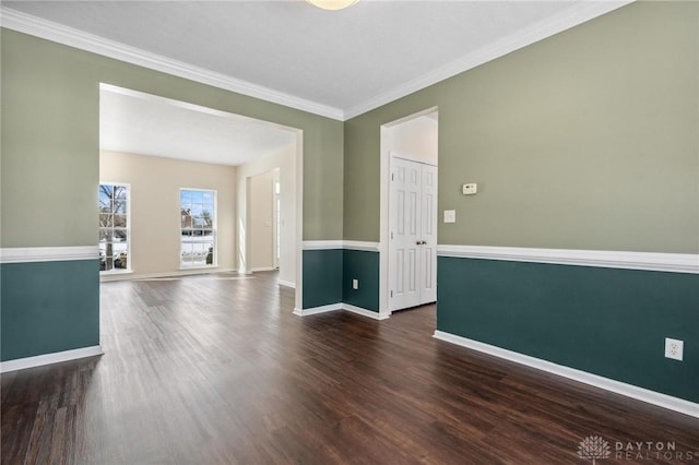 spare room featuring dark wood-type flooring, baseboards, and ornamental molding