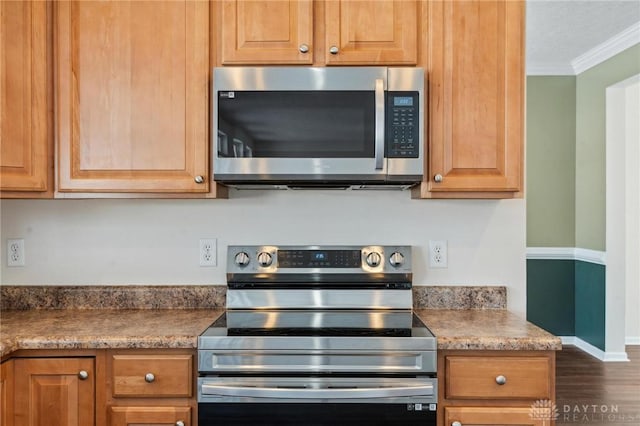 kitchen featuring ornamental molding, dark wood-style floors, baseboards, and stainless steel appliances