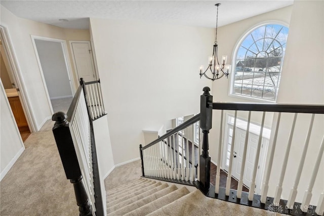 stairs with an inviting chandelier, carpet flooring, and baseboards