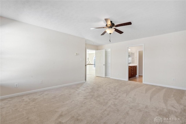 unfurnished bedroom featuring light carpet, connected bathroom, baseboards, and ceiling fan