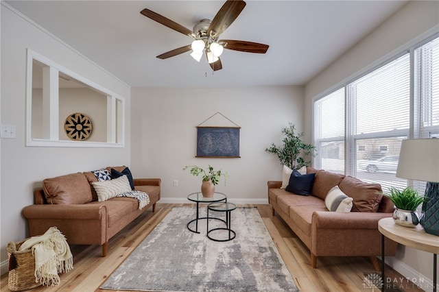 living area featuring light wood-style floors, ceiling fan, and baseboards