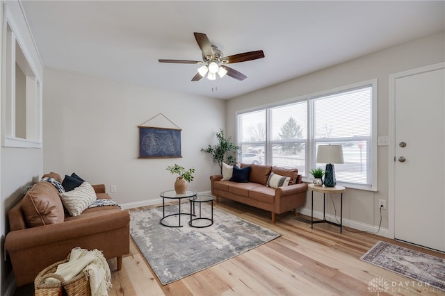 living area featuring light wood-style floors, baseboards, and a ceiling fan