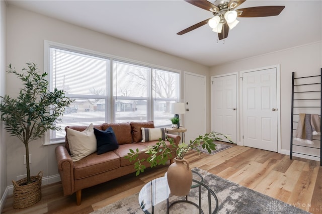 living area featuring ceiling fan, baseboards, and wood finished floors